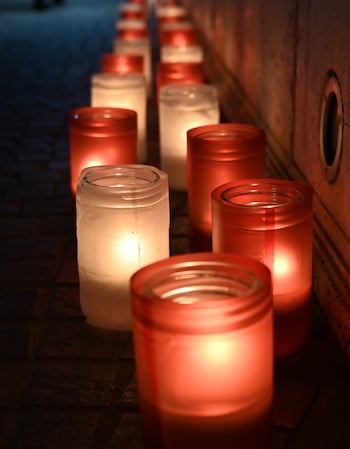Une suite de bougies allumées posées au sol