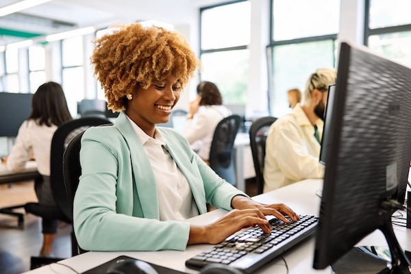 comment être productif : une femme africaine utilisant un ordinateur portable dans un coworking plein de gens