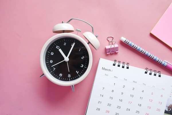 Réveil, calendrier, crayon, posés sur un fonds rose : concept de la routine